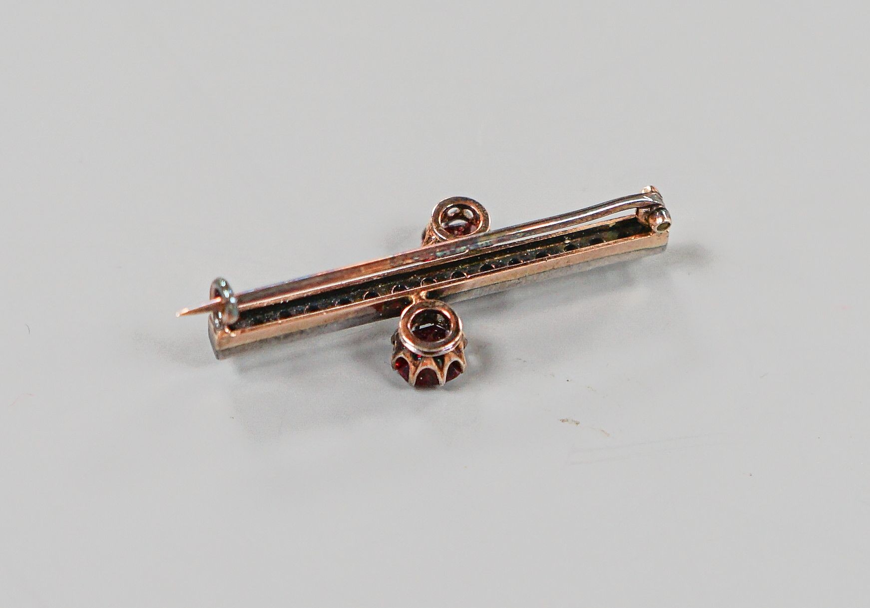 A yellow metal, rose cut diamond chip and two stone red doublet set bar brooch, 36mm, gross weight 3.7 grams.